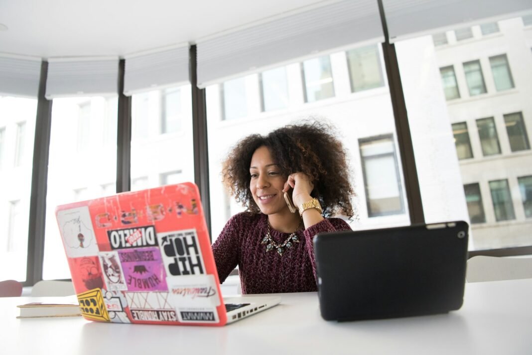 Got a Foreign Remote Role? Protect Your Pay Before You Start Black woman on a phone call at her desk with a laptop, agreeing payment terms for remote work