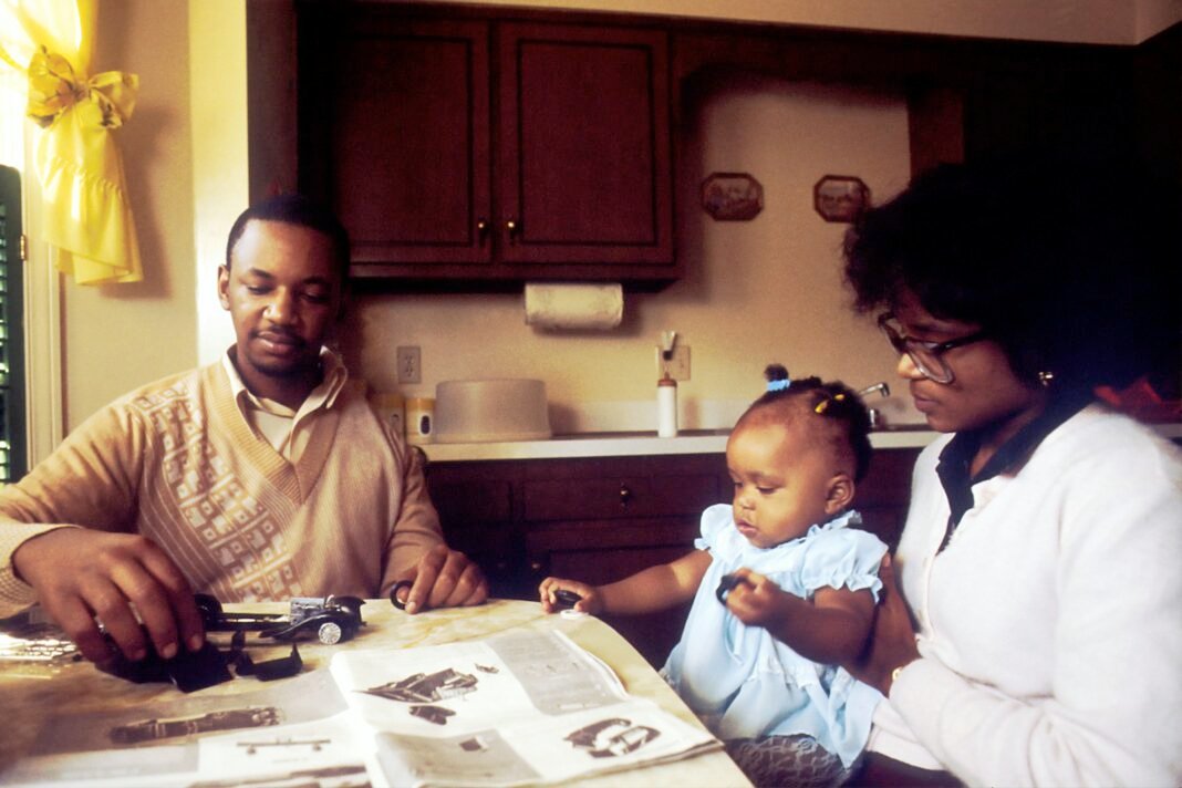 Black couple sitting together at a table with their child, reviewing papers and planning household finances