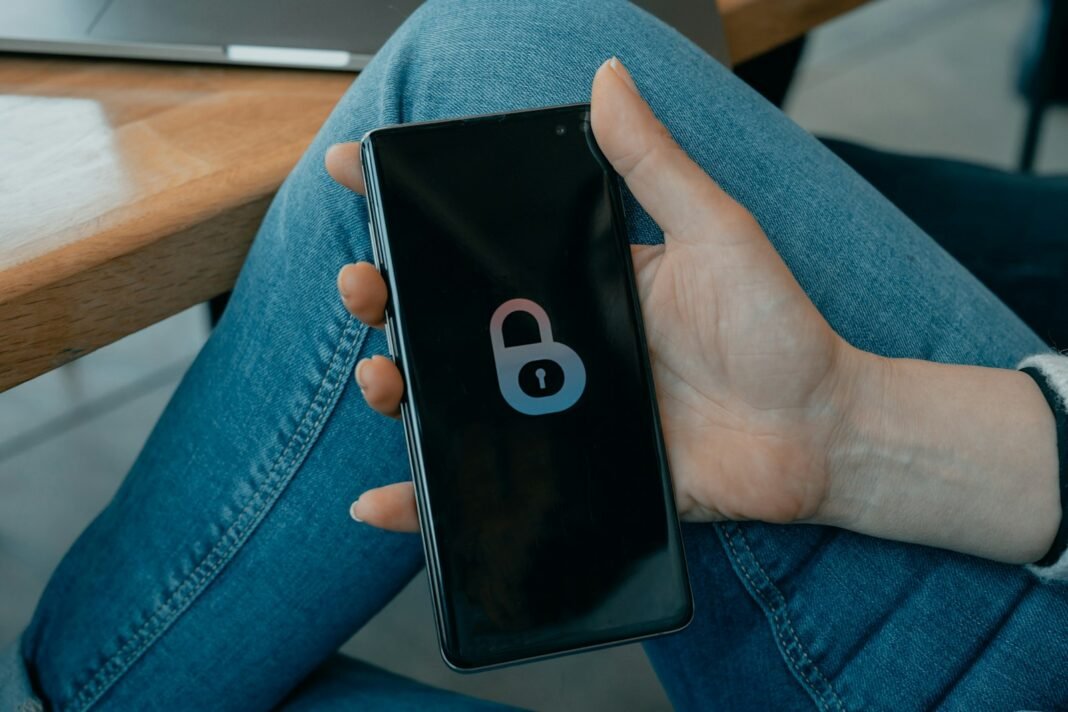 How to Avoid Online Scams in Nigeria: A Practical Cybersecurity Guide Hand holding a smartphone showing a security lock screen