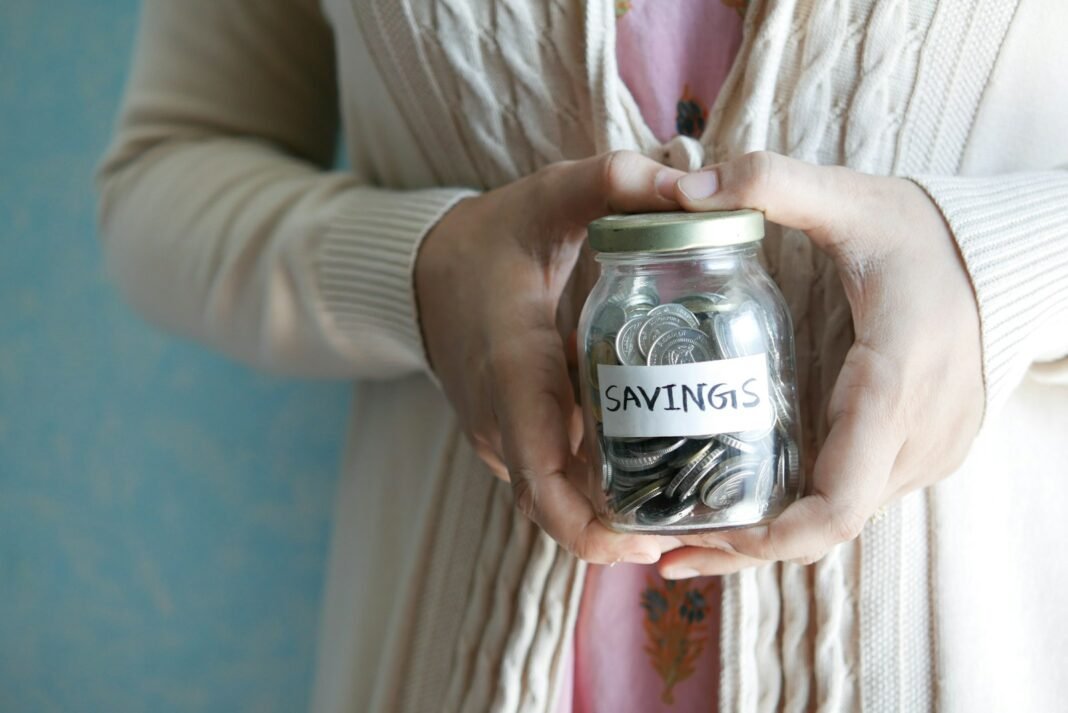 How to Build an Emergency Fund in Nigeria Woman holding a savings jar of coins, representing an emergency fund