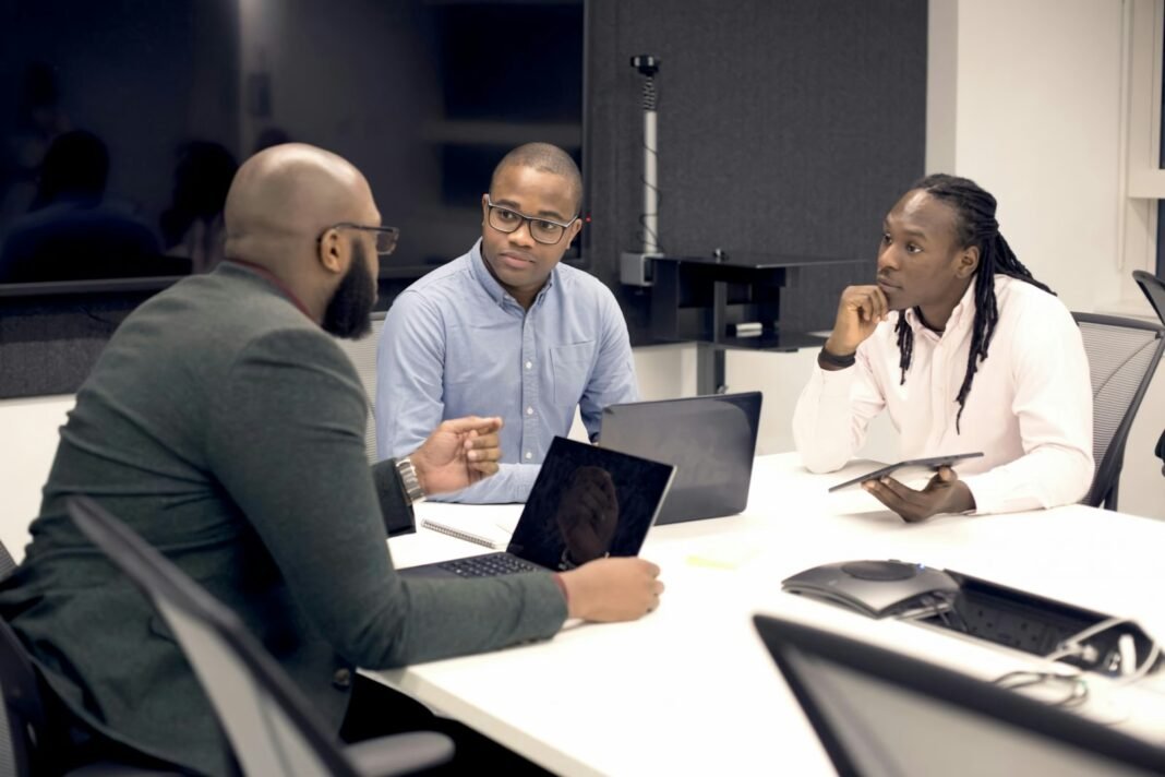 Team of Black professionals meeting around a table with laptops to agree how they use AI at work