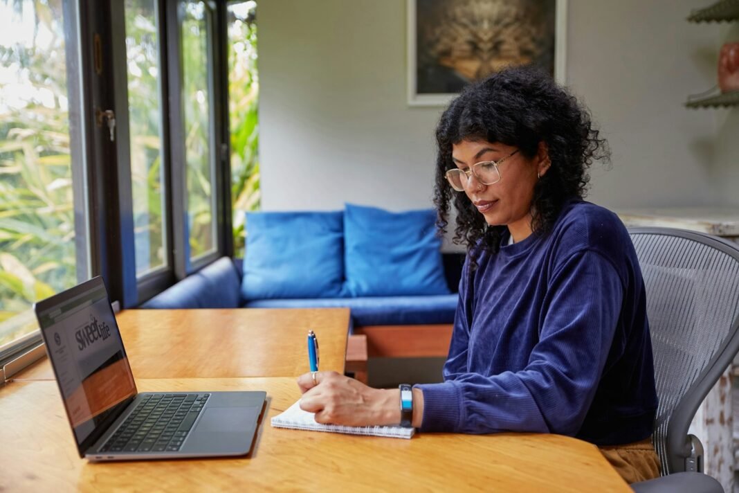 Black woman working from home at a table with a laptop and notebook
