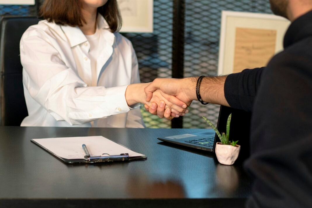 How to Negotiate Your Salary With Confidence Two professionals shaking hands across a desk after a negotiation