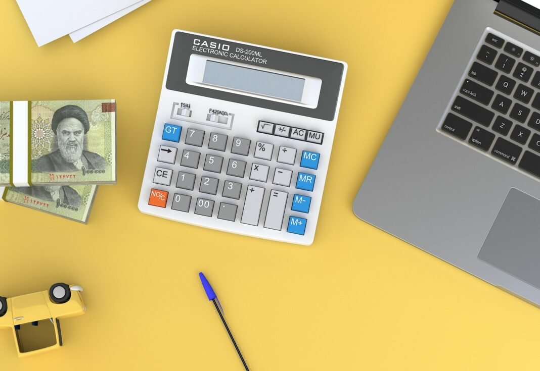 How to Create a Budget That Actually Works (50/30/20 Rule and Alternatives) Calculator next to a laptop on a desk, used for budgeting