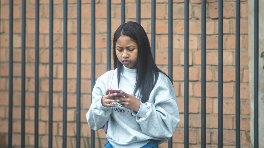Your CV, Your BVN, Your Client’s Data: Protect It at Work Young African woman checking her phone carefully, thinking about protecting her personal data