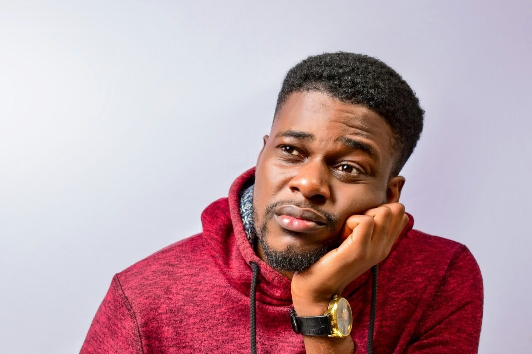 Borrowed ₦20,000 From a Loan App? Read This Before the Next One Worried young Nigerian man resting his chin on his hand, thinking about debt
