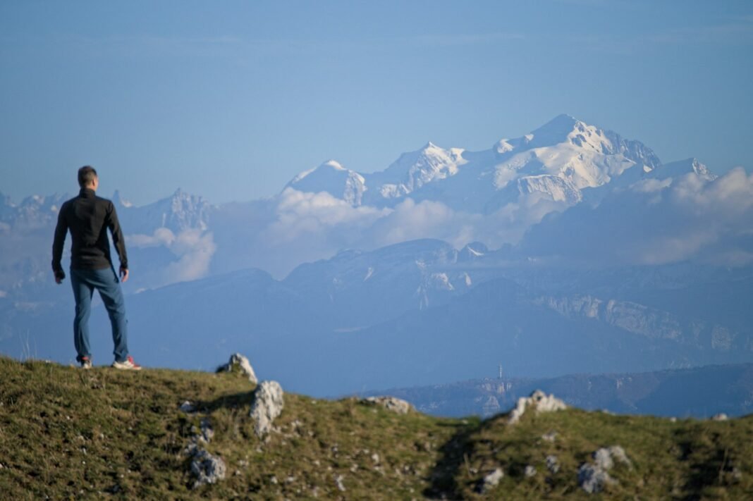 How to Overcome the Fear of Failure: 8 Practical Strategies Man standing on a grassy hill looking towards distant mountains, symbolising facing fear of failure