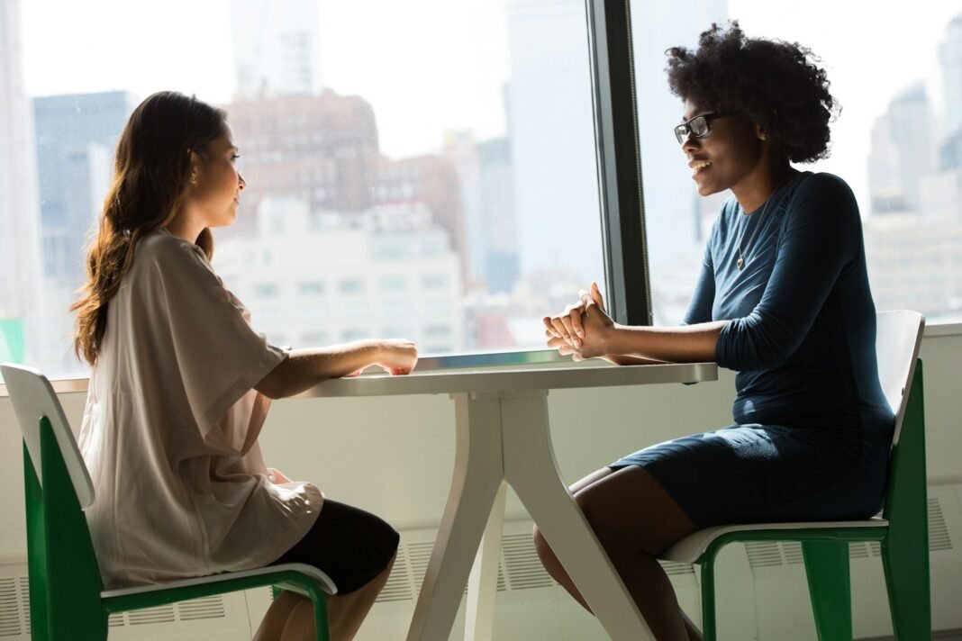Ready to Talk to Someone? How to Find a Therapist in Nigeria Two women sitting at a table having a calm conversation, like a counselling session