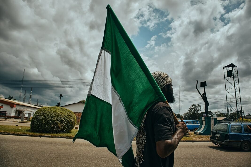 Your PVC Is Your Voice: How to Check Your Status and Collect It Before January Young Nigerian woman in a hijab holding the green-white-green Nigerian flag outdoors