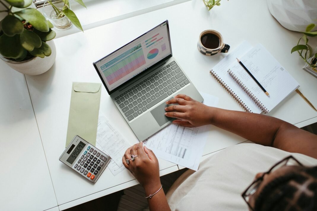 Living on ₦70k, ₦150k, ₦300k or ₦500k a Month? Real Budget Plans for 2026 Black woman at a table with a laptop, notebook and papers, planning a monthly budget